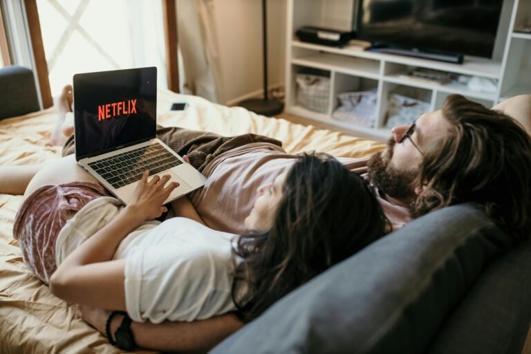A cozy couple lounging in bed, streaming Netflix together on a laptop, enjoying a peaceful moment with the vpn on for privacy and protection