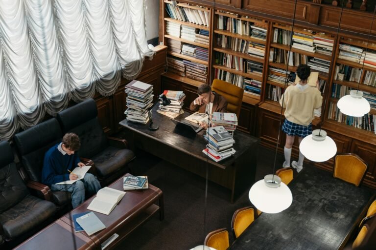 High-angle view of students studying in a classic library with bookshelves and vintage lighting.